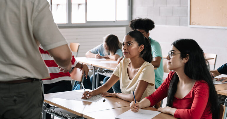 Hispanic and Latin female teenager students listening with attention to teacher explanations in Secondary School. Learning and Education in College